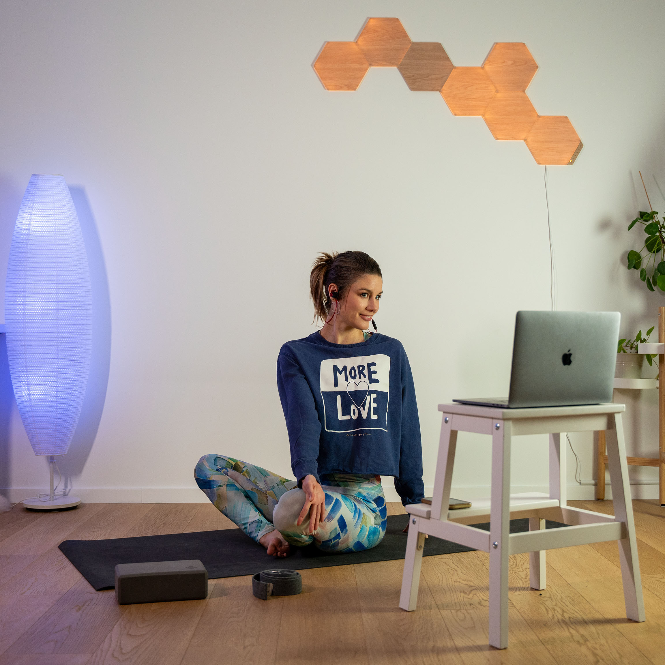 Klara Bright kneeling on the mat and smiling into her laptop as she is encouraging her individual client during an 1:1 online yoga session