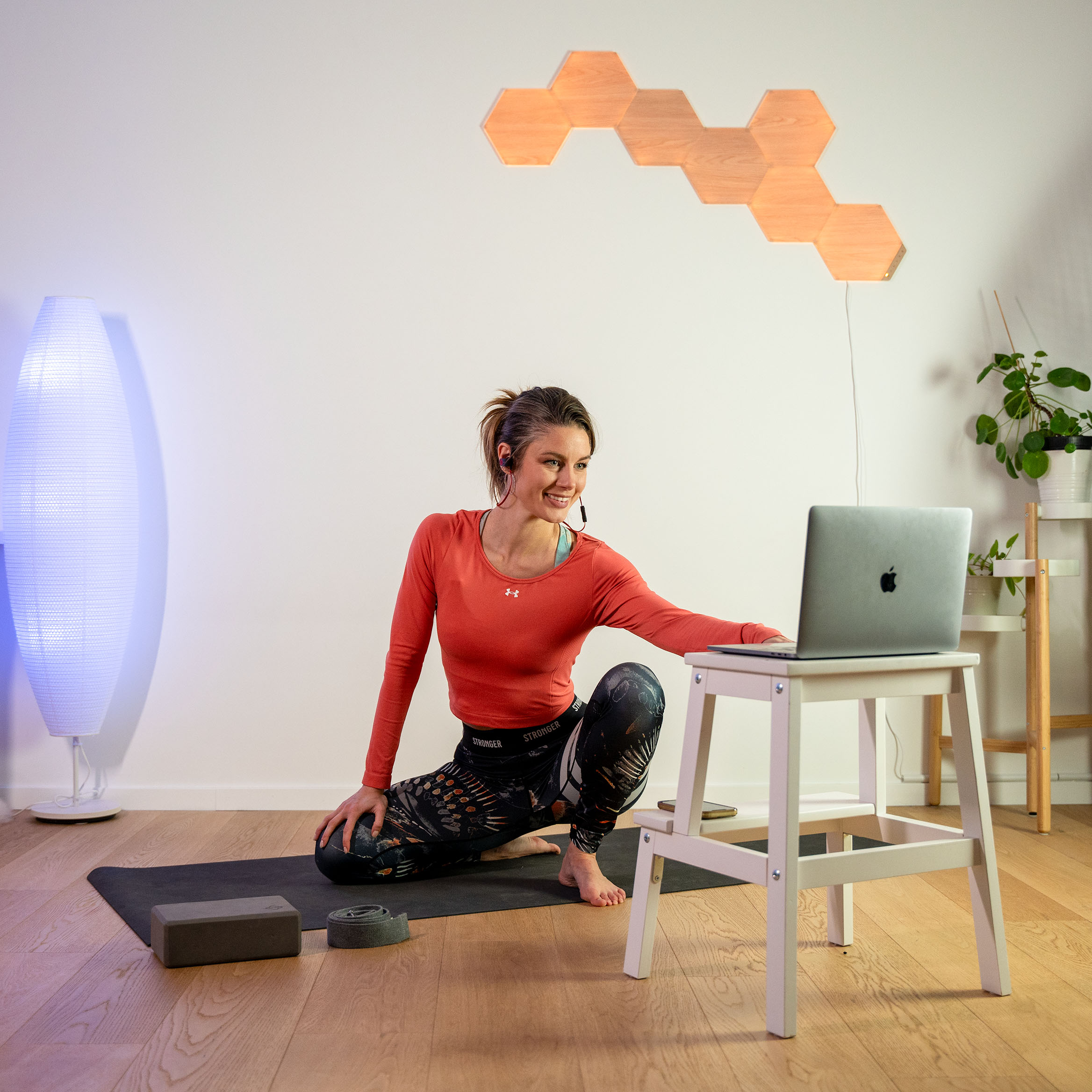 Klara Bright kneeling on her mat, smiling into her laptop as she is encouraging her individual client during an 1:1 online session